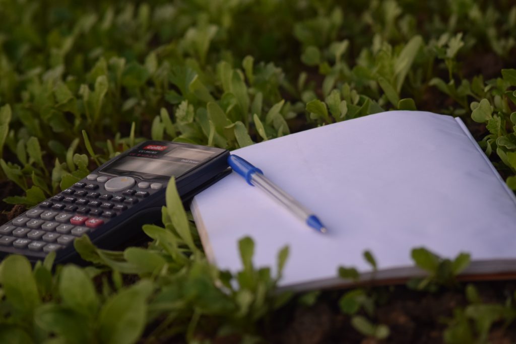 Calculator and Notebook with Pen on the Grass
