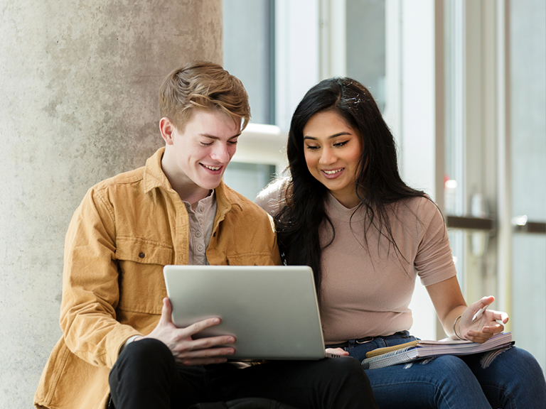 Students smiling and us a computer