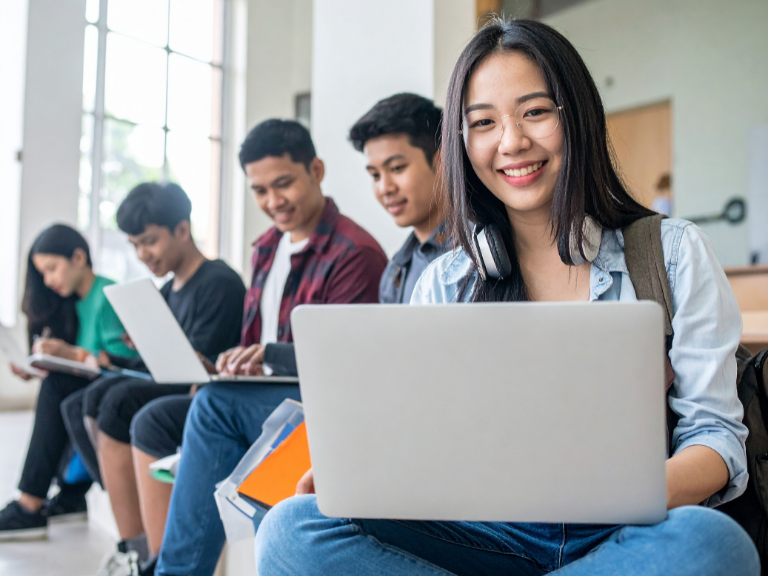 Smiling students using laptop computers