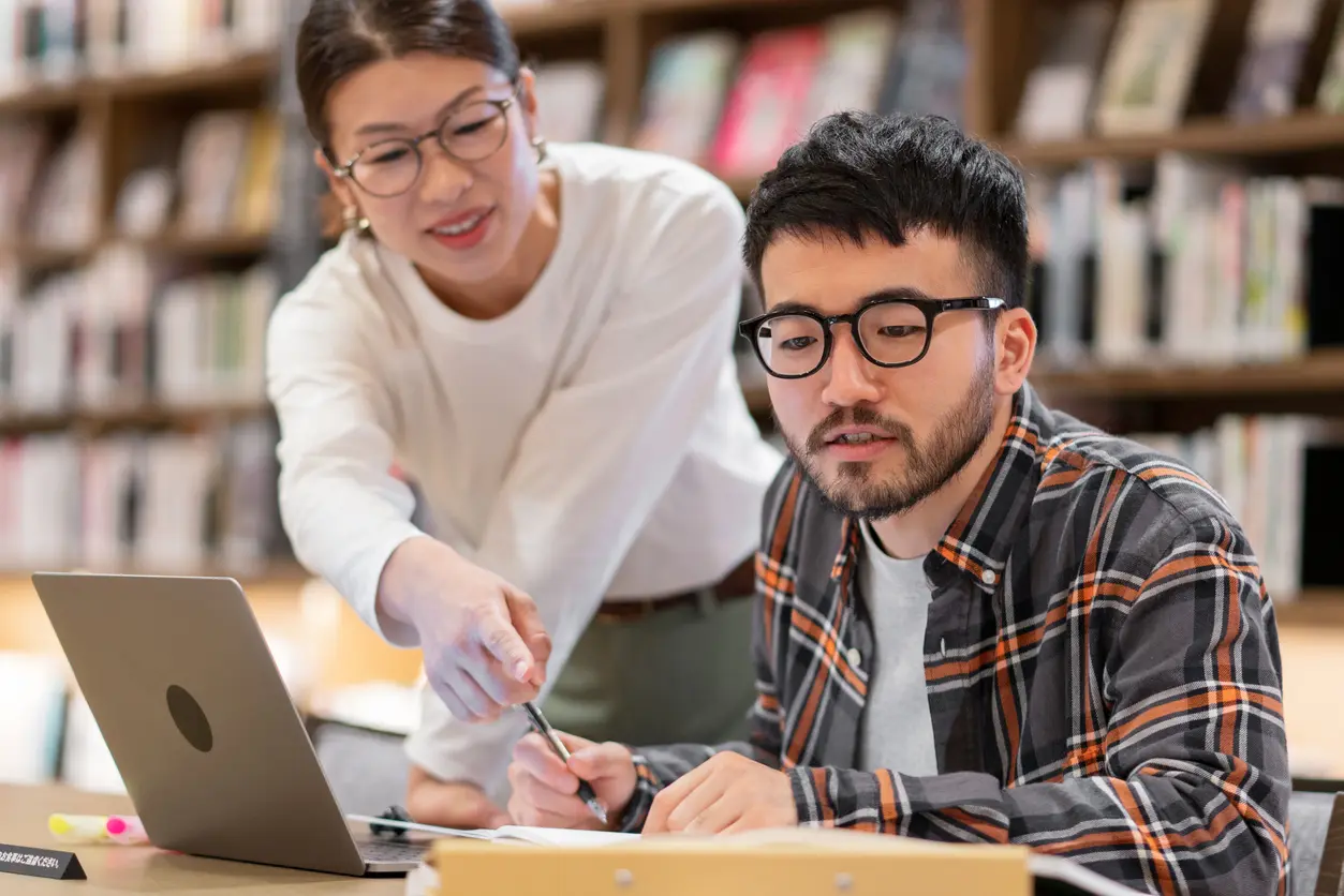 Professor talking to a student in a library 